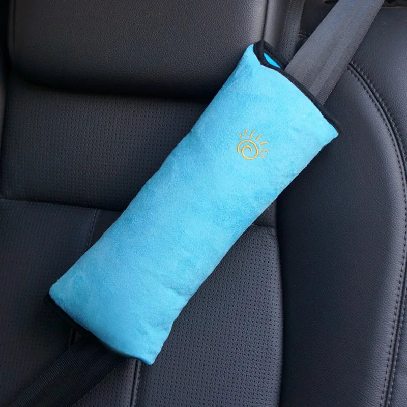 A bright blue foam shoulder cushion attached to a car seat belt strap on a dark gray car seat.