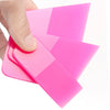 A hand is holding and using a pink anti-scratch PPF squeegee tool for window tinting or film installation.