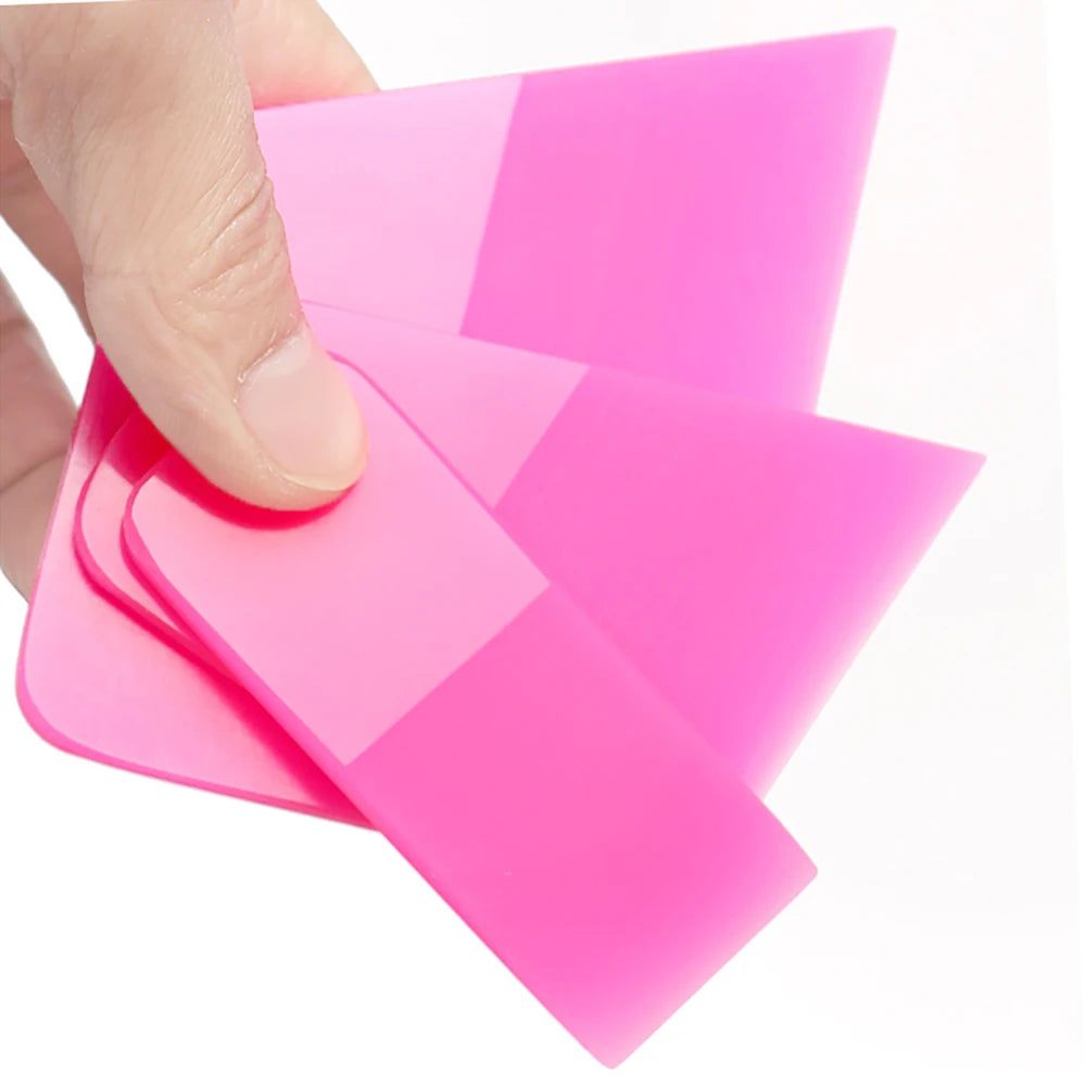 A hand is holding and using a pink anti-scratch PPF squeegee tool for window tinting or film installation.