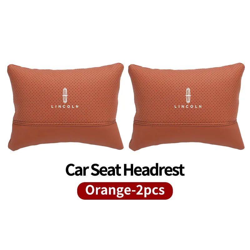Two orange Lincoln car seat headrest neck support pillows.