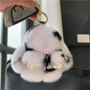 A white and black plush bunny keychain with soft fur attached to a gold ring.