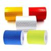 A collection of rolled high-visibility reflective tape in yellow, red, white, blue, and lime green.