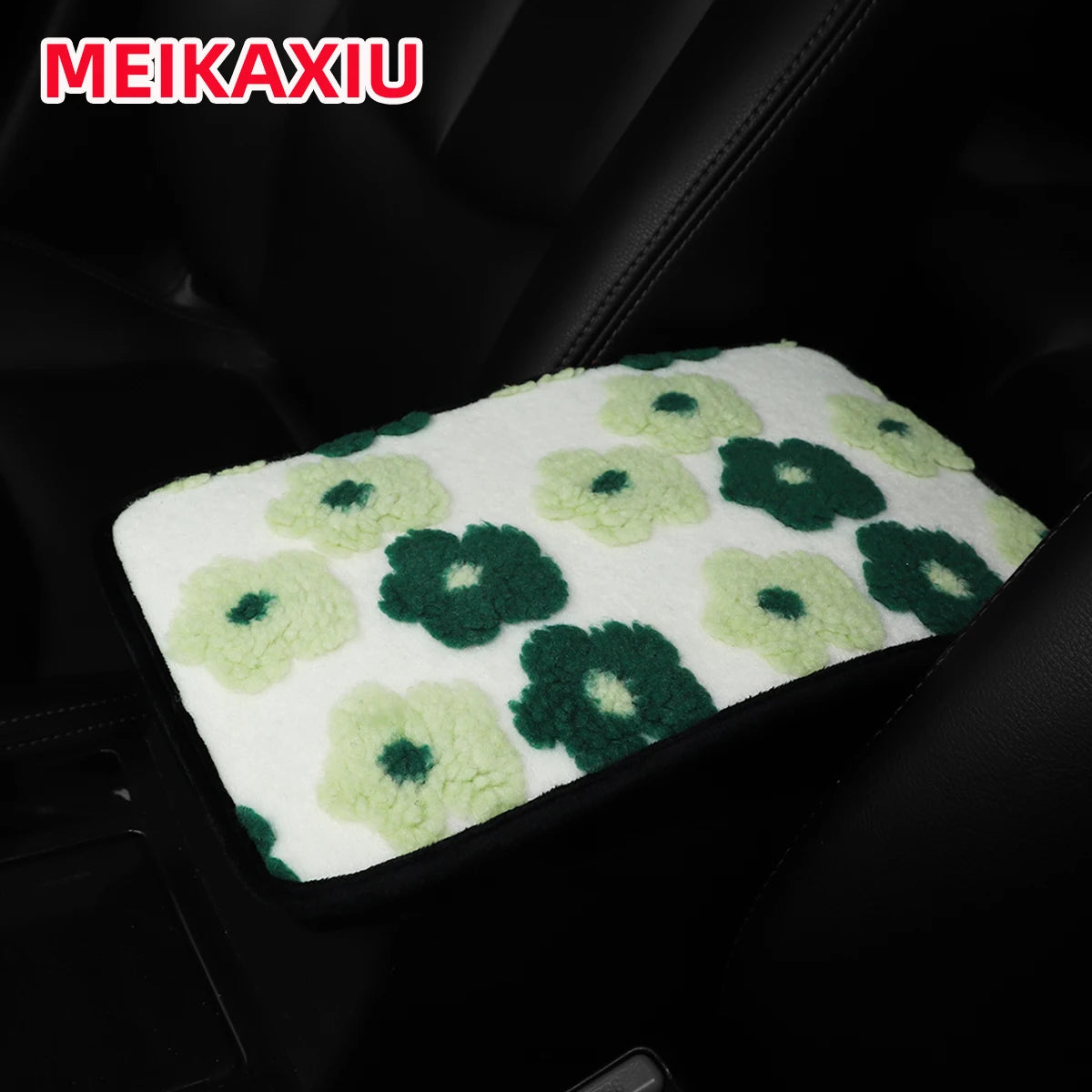 A green and white floral plush cushion placed on a black car armrest.