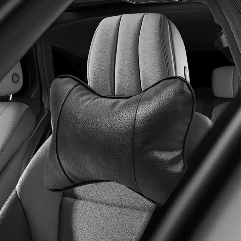 A close-up view of a black ergonomic auto headrest cushion for neck support placed on a car seat.