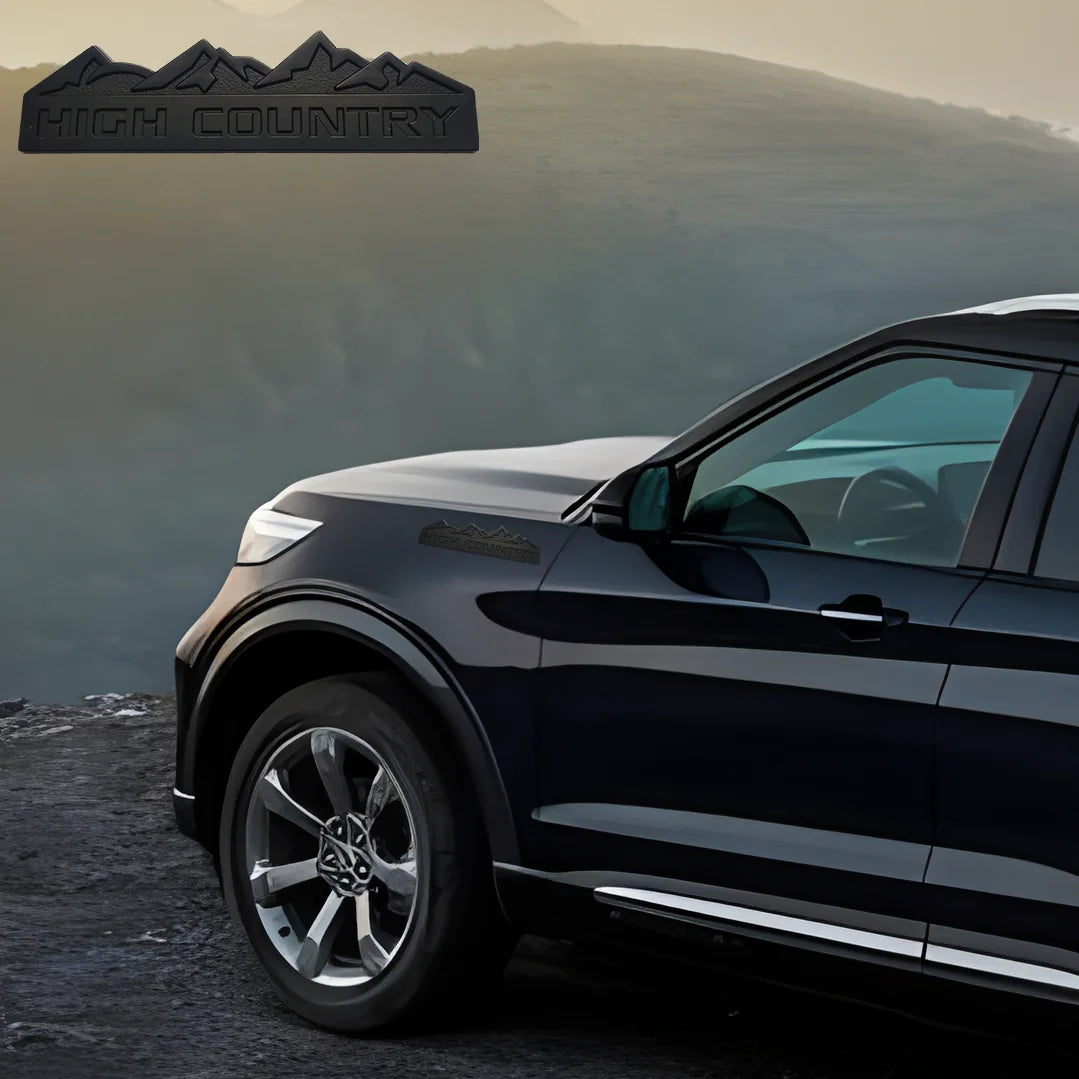 A dark SUV is parked on a rugged landscape with a high country decal visible on the vehicle.