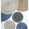 A collection of round, textured placemats made from natural fibers in shades of beige, gray, and blue.