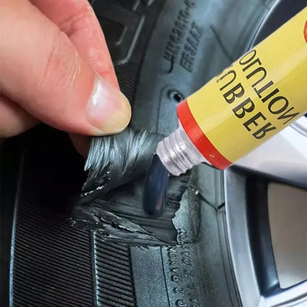 Una mano aplica pegamento para reparar neumáticos a un tubo interior negro usando un aplicador de pegamento amarillo.