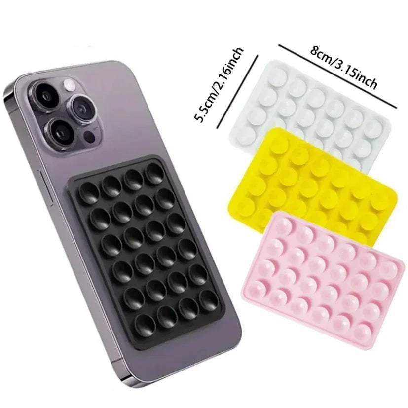 Un smartphone est montré à côté de trois supports en ventouses en silicone blancs, jaunes et roses.