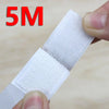 A hand is holding a white self-adhesive hook and loop tape strip for organization.
