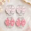 Pink glitter bow cable protectors for lightning and type-C chargers displayed on a light background.