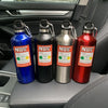 Three insulated stainless steel water bottles in blue, black, and red resting on a car interior panel.