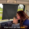 A woman is looking out of a car window at a black retractable sunshade rolled down.