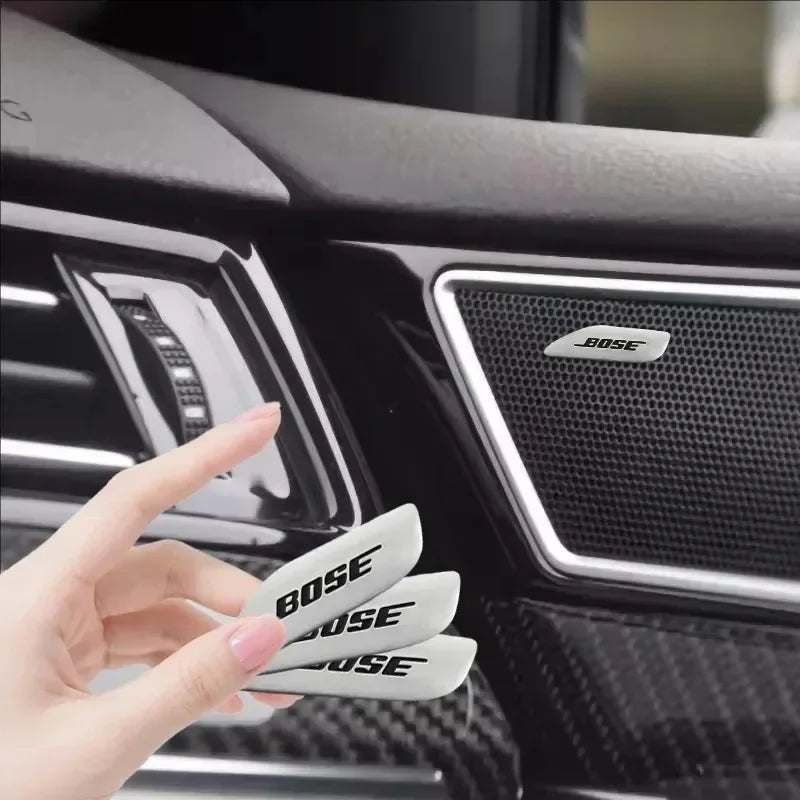 Close-up of black car audio emblems featuring the Bose logo on a vehicle interior panel.