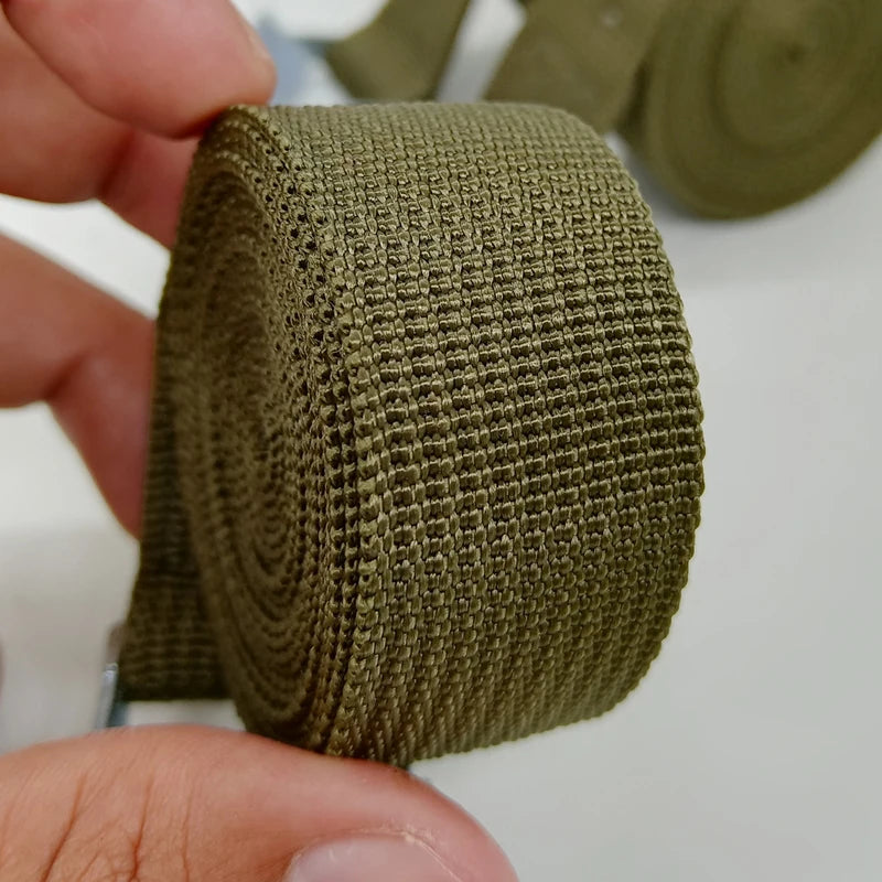 A close-up of a coiled olive green heavy duty cargo strap with a woven texture.