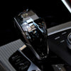 A close-up of a black crystal gear shift knob lever for BMW models resting on a car console.