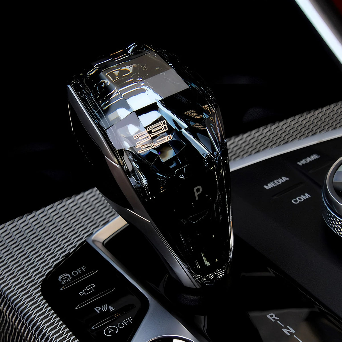 A close-up of a black crystal gear shift knob lever for BMW models resting on a car console.