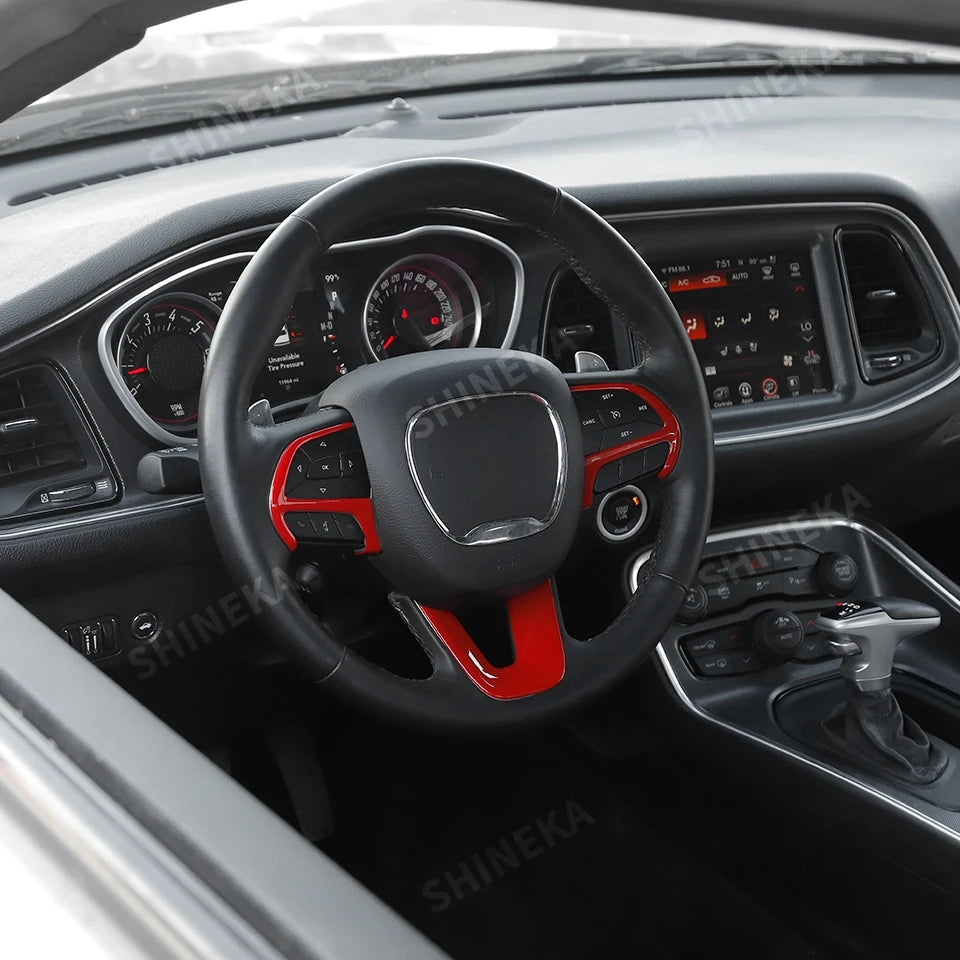 Interior view of a car steering wheel with a black cover featuring red accents and controls.