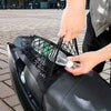 A hand is placing a clear bottle into a black cargo net attached to a black motorcycle seat.