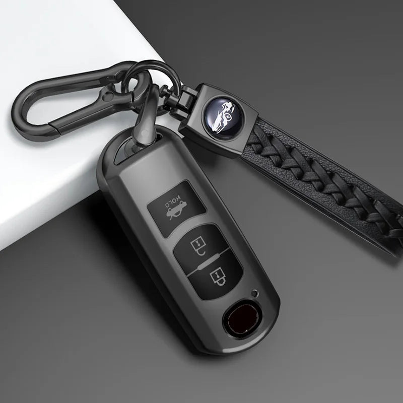 A close-up of a universal car key cover for Mazda models attached to a black leather strap and a metal keyring.