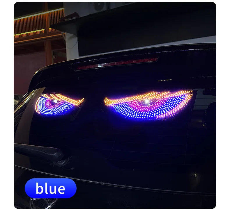 Close-up of a black car displaying an RGB dynamic demon eye light display on the headlights.