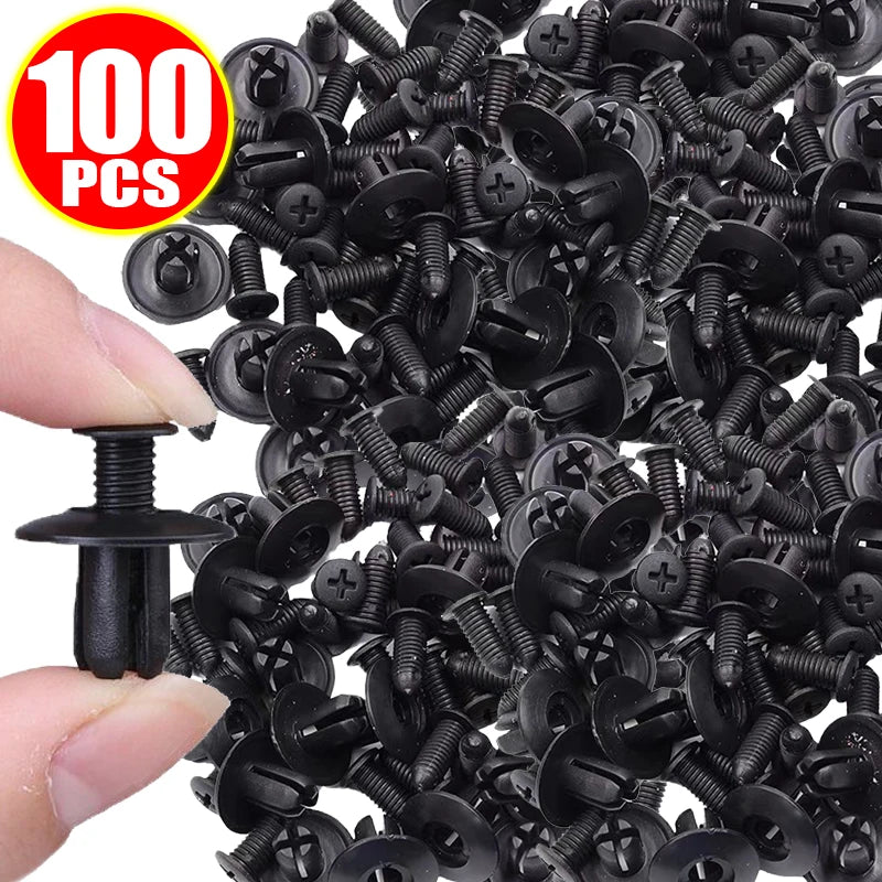 A close-up view of numerous black plastic rivets and push pins for car bumpers, showing a hand holding one fastener.