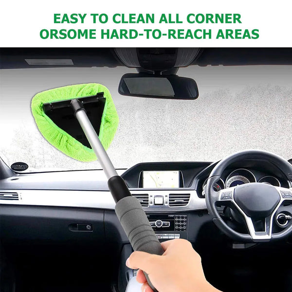 A hand is using a telescopic windshield cleaning brush to clean the interior of a car.