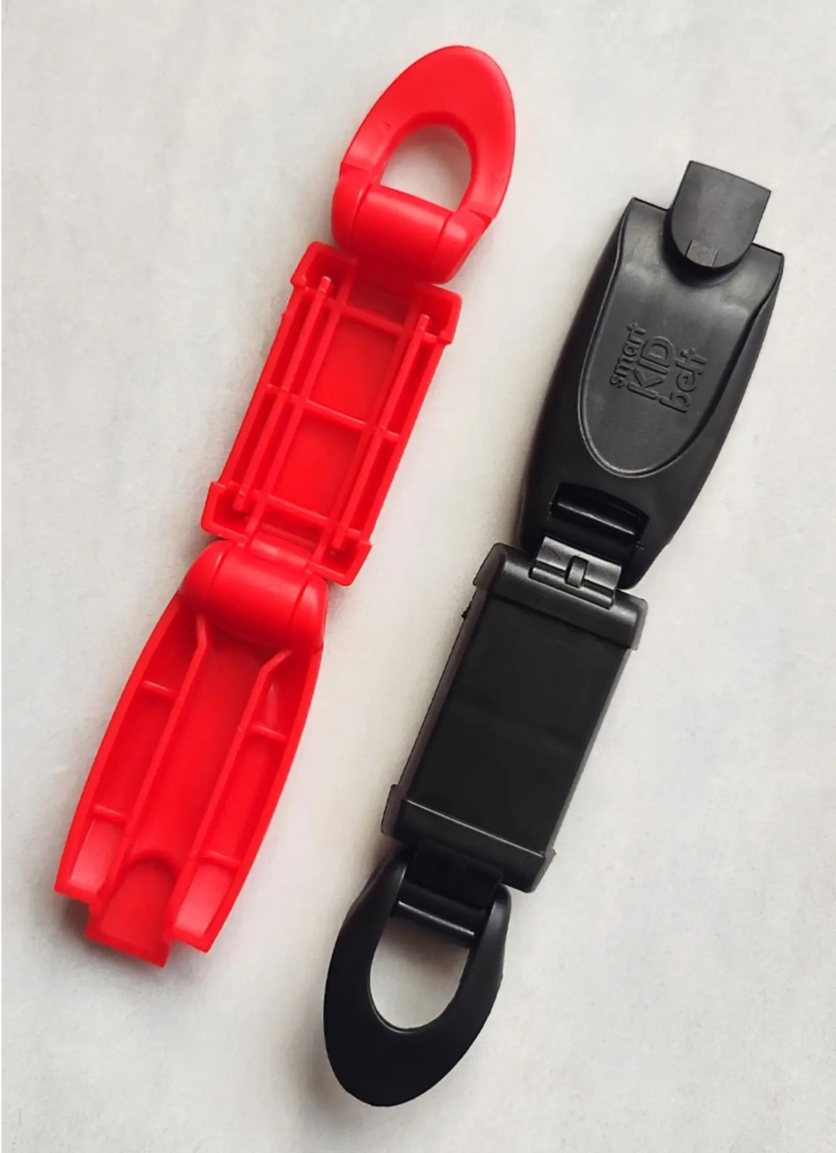 A bright red comfort-adjustable seat belt clip and a black version are shown against a white background.