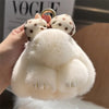 A white plush bunny keychain with soft fur and gold ring being held by a hand.