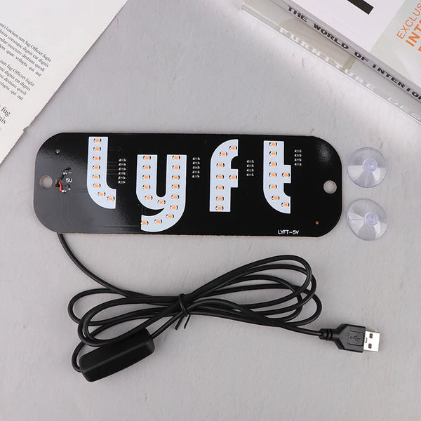 A black customizable LED taxi signal lamp with white letters and a coiled black wire is shown on a white surface.