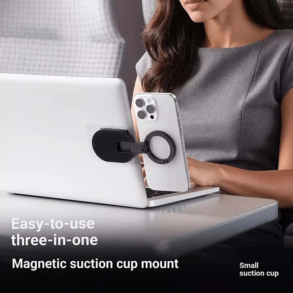 A woman is using a three-in-one magnetic suction cup mount to hold a phone while working on a laptop.