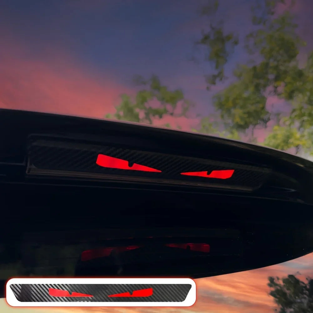 Gros plan sur le feu arrière d'une voiture noire avec un autocollant œil de monstre rouge.