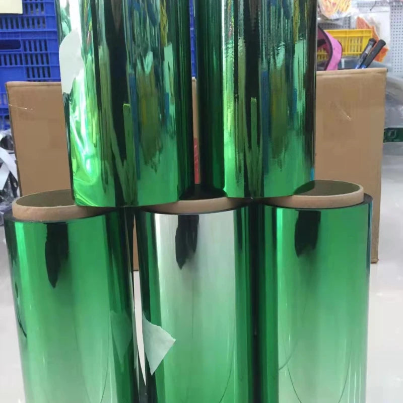 Drei zylindrische Rollen grüner Farbverlauf-Scheibenfolie für Autos in einer Vitrine.