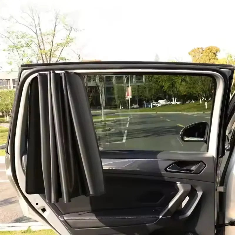 A close-up view of a dark gray car window with two magnetic sun shades partially deployed.