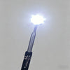 A close-up view of a telescoping magnetic pickup tool with an LED light shining brightly.