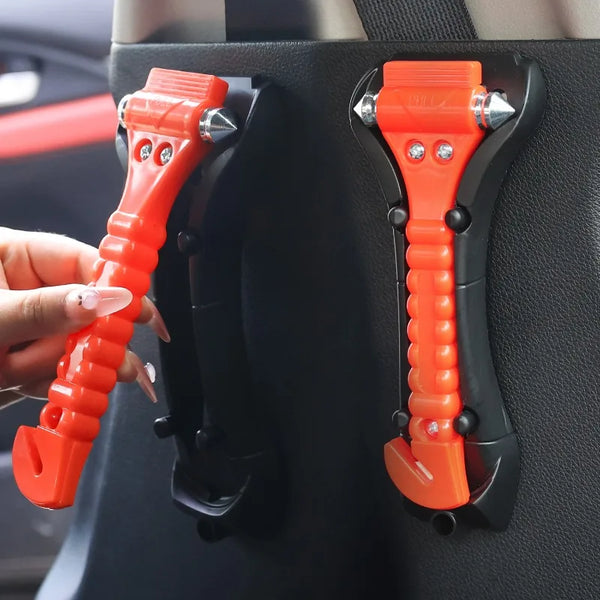 A hand holds an orange heavy-duty emergency window breaker and seatbelt cutter tool against a dark car interior panel.