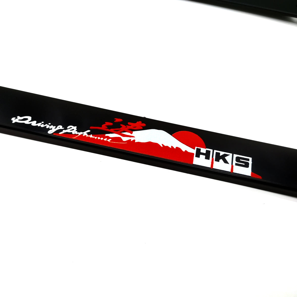 Black license plate frame decoration featuring a red dragon and white silhouette against a red sun, with the letters HKS.