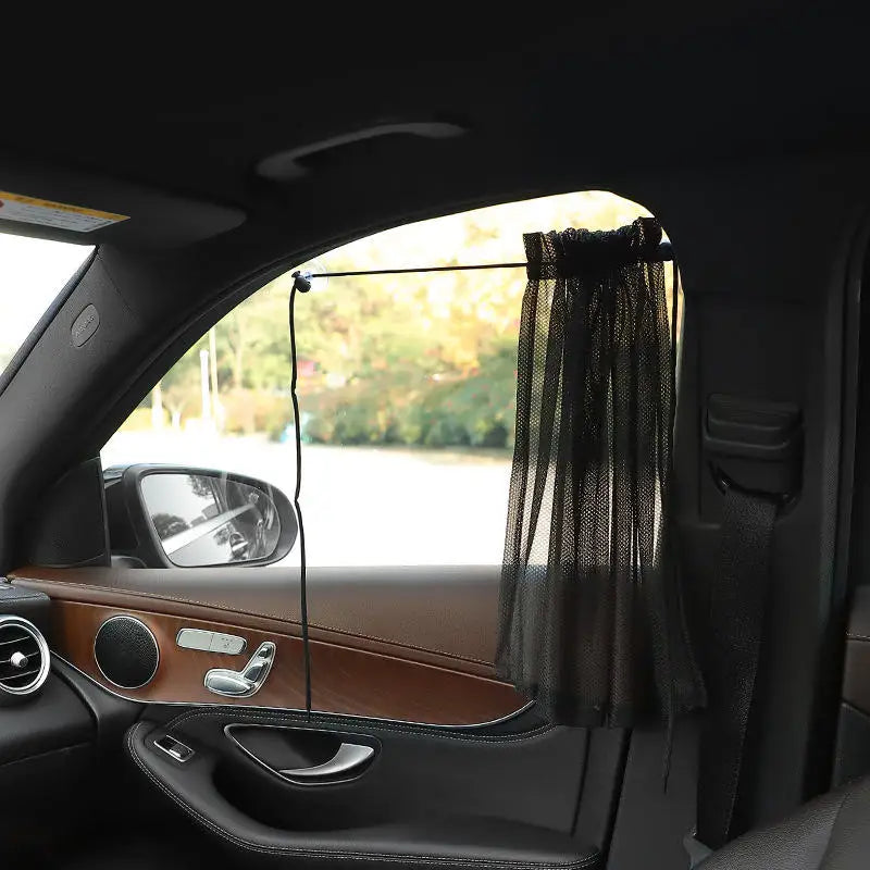 A black suction cup window sunshade is installed in a car window, partially covering the view.