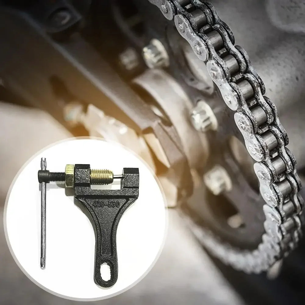 A close-up view of a universal chain breaker tool with a metal pin and lever, used for removing motorcycle or bicycle chains.