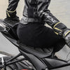 A person wearing black leather gear is sitting on a motorcycle with seat covers.