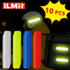 A set of ten reflective safety stickers or tape pieces displayed next to a yellow glove and a dark electronic device.