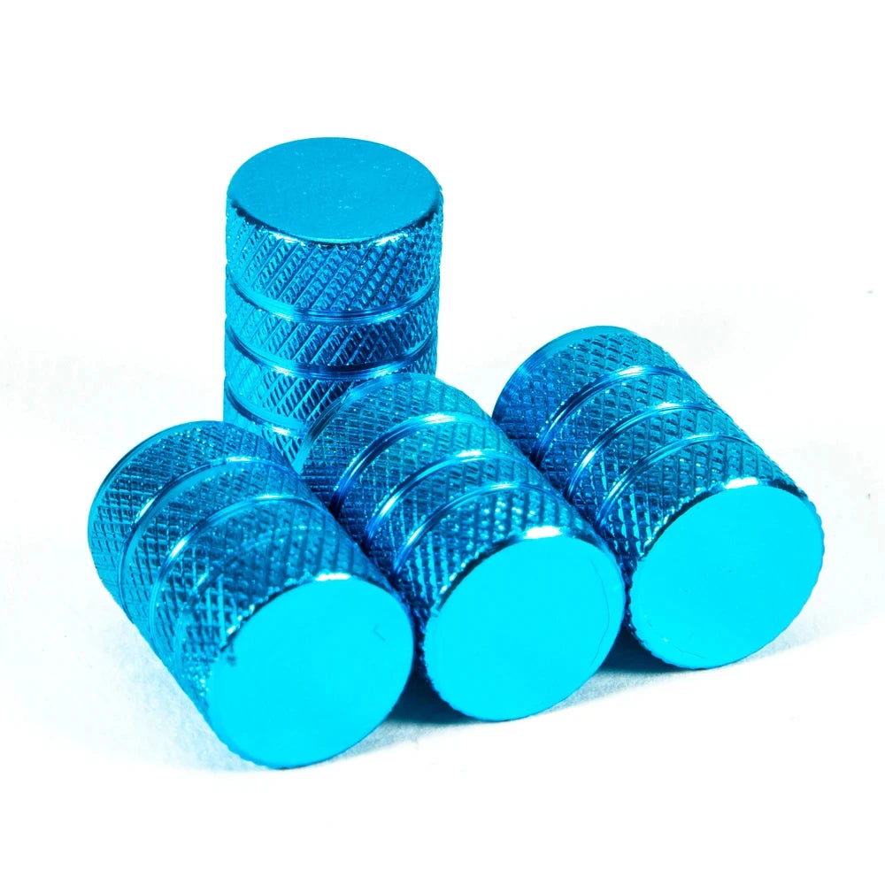 A set of bright blue aluminum tire valve caps, cylindrical in shape.