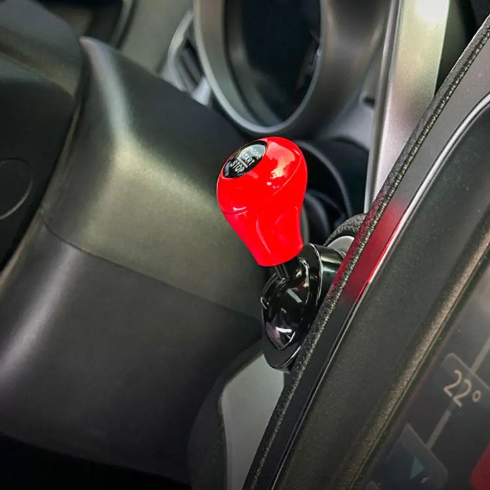 Close-up of a red cylindrical car start button accessory mounted on a vehicle's interior panel.