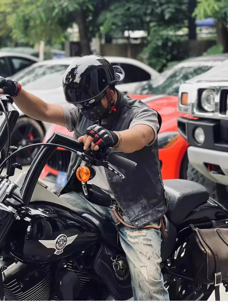 Eine Person trägt einen schwarzen Vintage-Motorradhelm und sitzt auf einem schwarzen Motorrad.