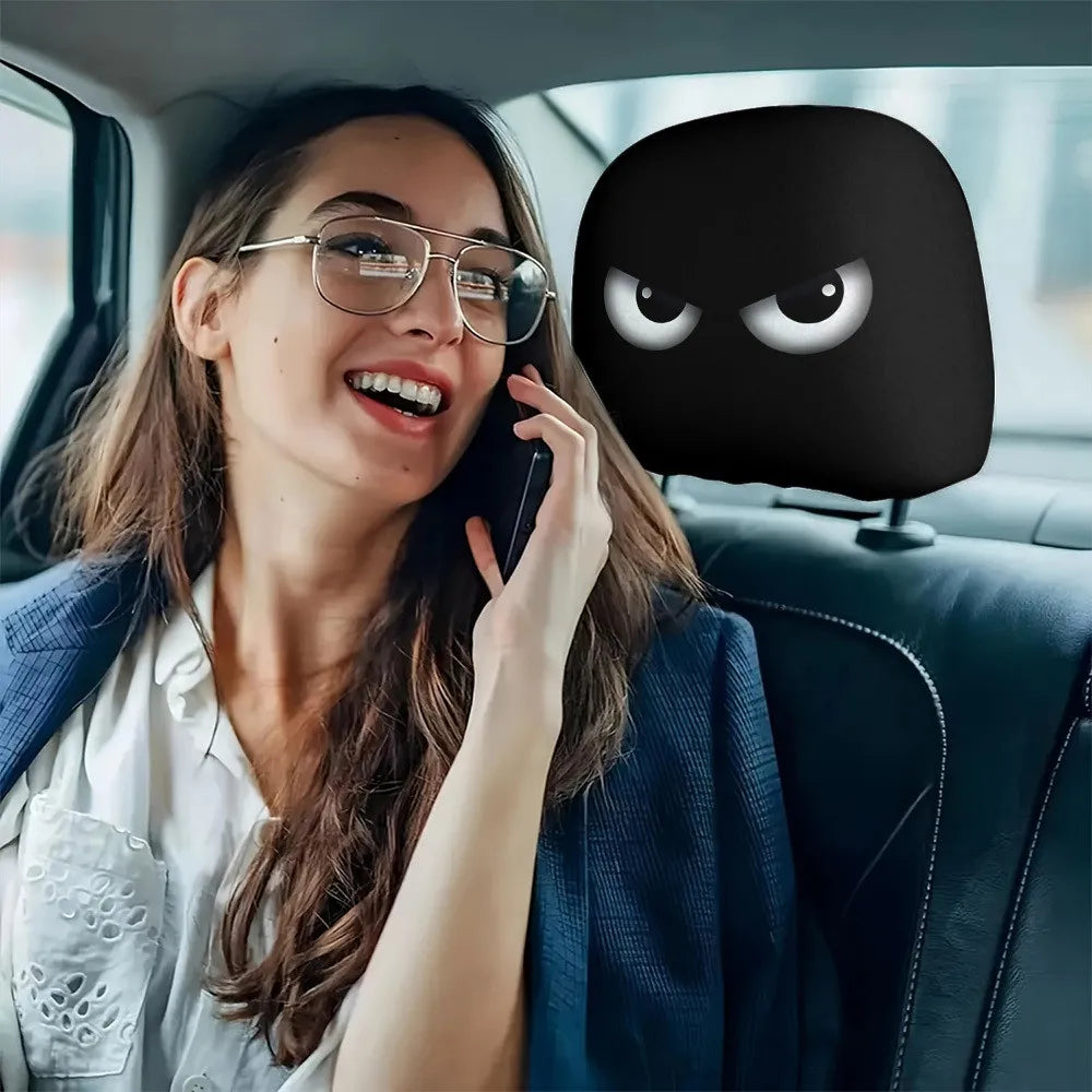A woman is using a phone while sitting in a car, with a black, funny slanted eyes headrest cover visible.