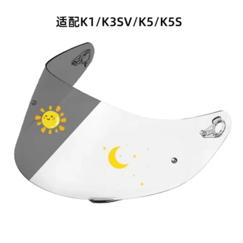A motorcycle helmet visor featuring a gray and white design with a sun and crescent moon graphic.