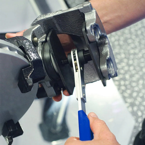 A hand is using a professional brake caliper spreader tool to open or close a brake caliper.