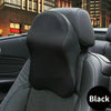 Black ergonomic headrest pillow for neck and lumbar support shown in a car seat interior.