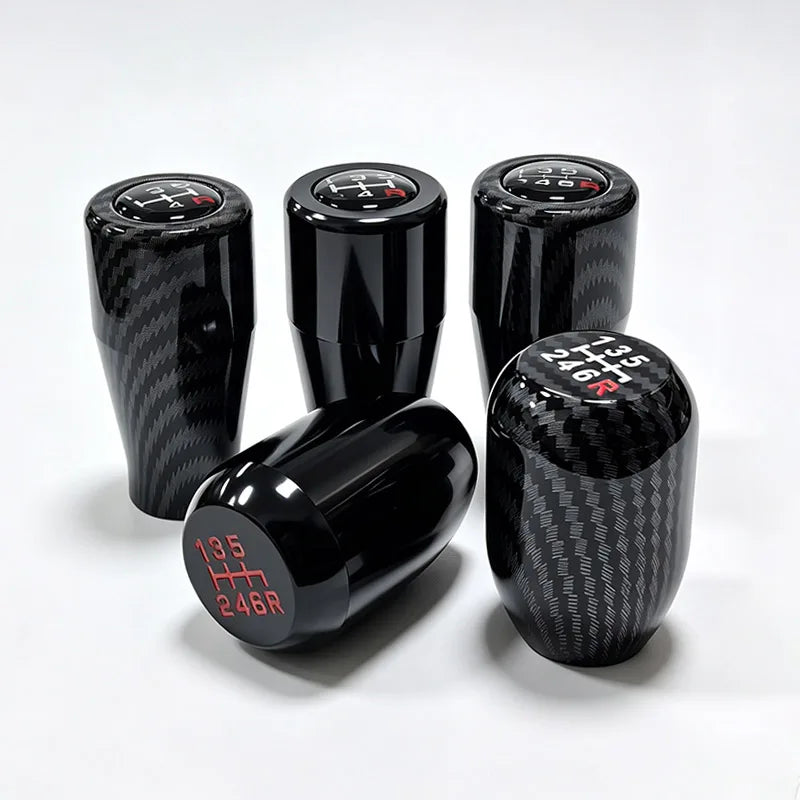 A set of four black carbon fiber gear shift knobs with red markings for a universal 5/6 speed manual transmission.