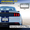 A black carbon fiber license plate frame cover for a blue and white car.