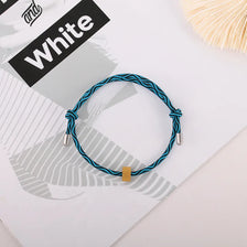 A blue braided heart-shaped fitness tracker bracelet is displayed on a white background next to a black label.